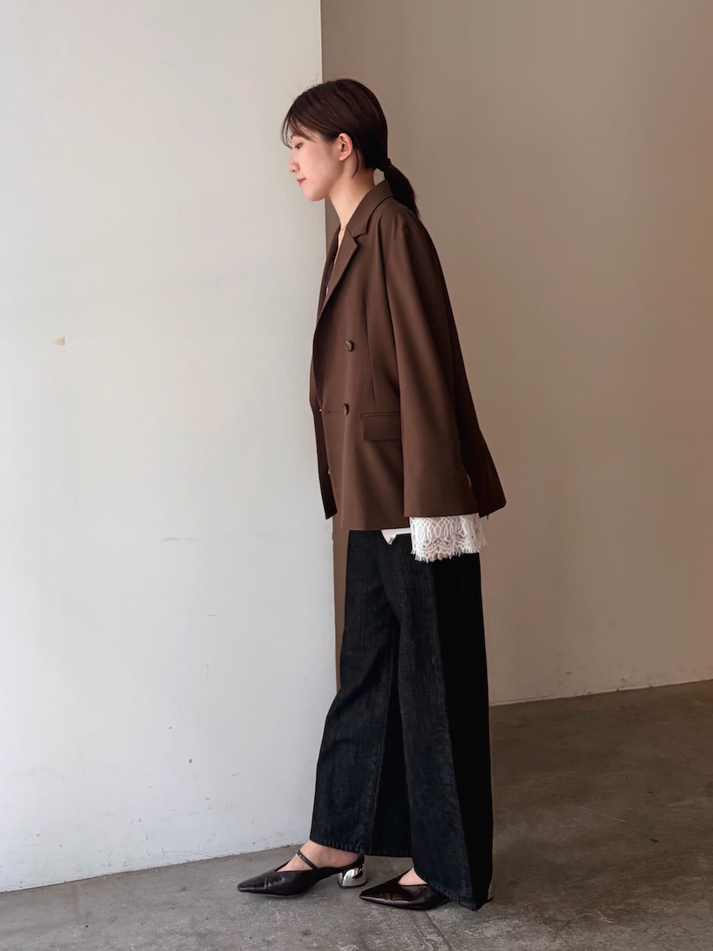 ブラック系のデニムパンツ、ブラウン系のテーラードジャケット、ホワイト系のキャミソールを着用したレディースの秋コーディネートの2枚目の写真