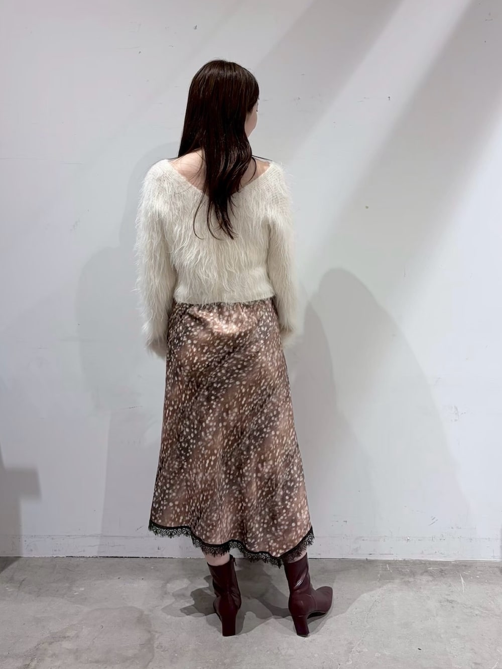 ホワイト系のニット/セーター、ブラウン系のスカート、レッド系のブーツを着用したレディースの夏コーディネートの4枚目の写真