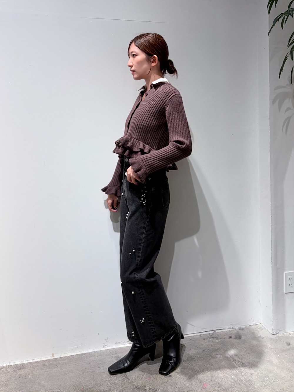 ブラック系のデニムパンツ、ブラウン系のニット/セーター、ブラック系のブーツを着用したレディースの秋コーディネートの2枚目の写真