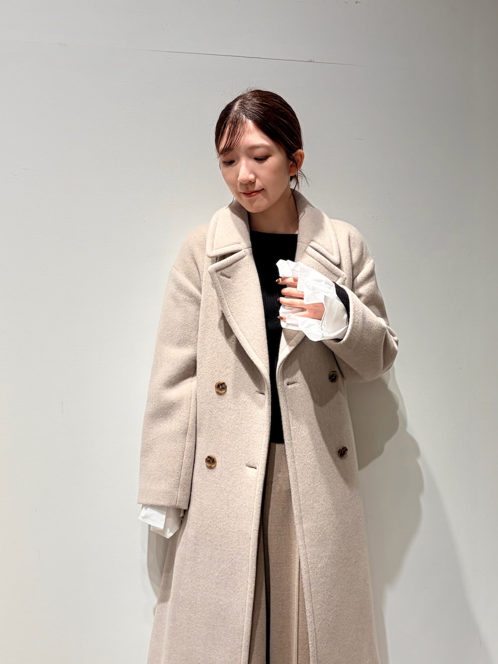 ホワイト系のチェスターコート、ベージュ系のその他パンツ、ブラック系のニット/セーターを着用したレディースの秋コーディネートの4枚目の写真