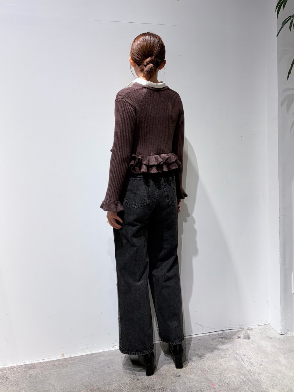 ブラック系のデニムパンツ、ブラウン系のニット/セーター、ブラック系のブーツを着用したレディースの秋コーディネートの3枚目の写真