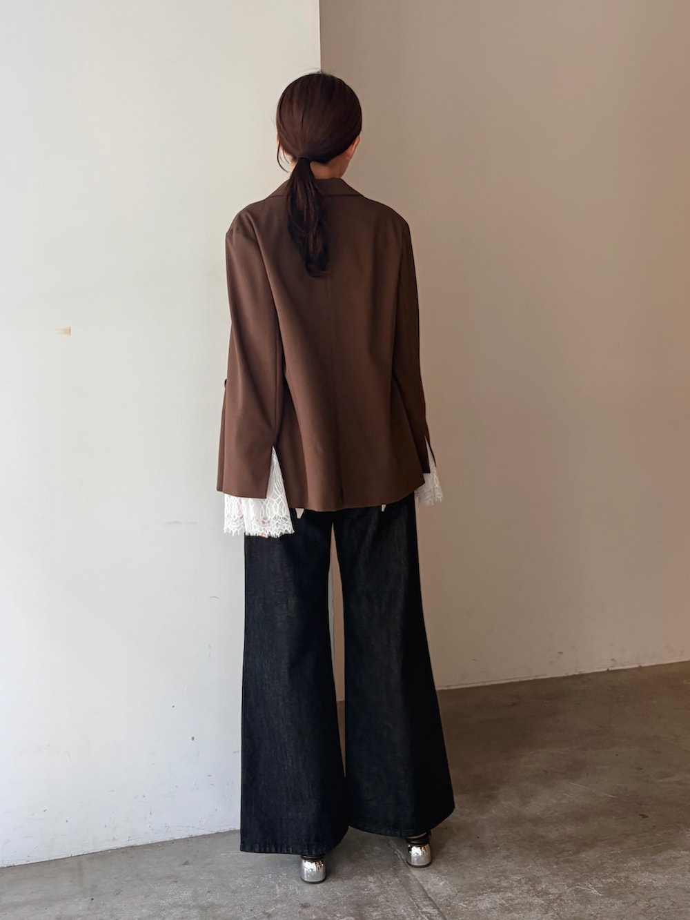 ブラック系のデニムパンツ、ブラウン系のテーラードジャケット、ホワイト系のキャミソールを着用したレディースの秋コーディネートの3枚目の写真