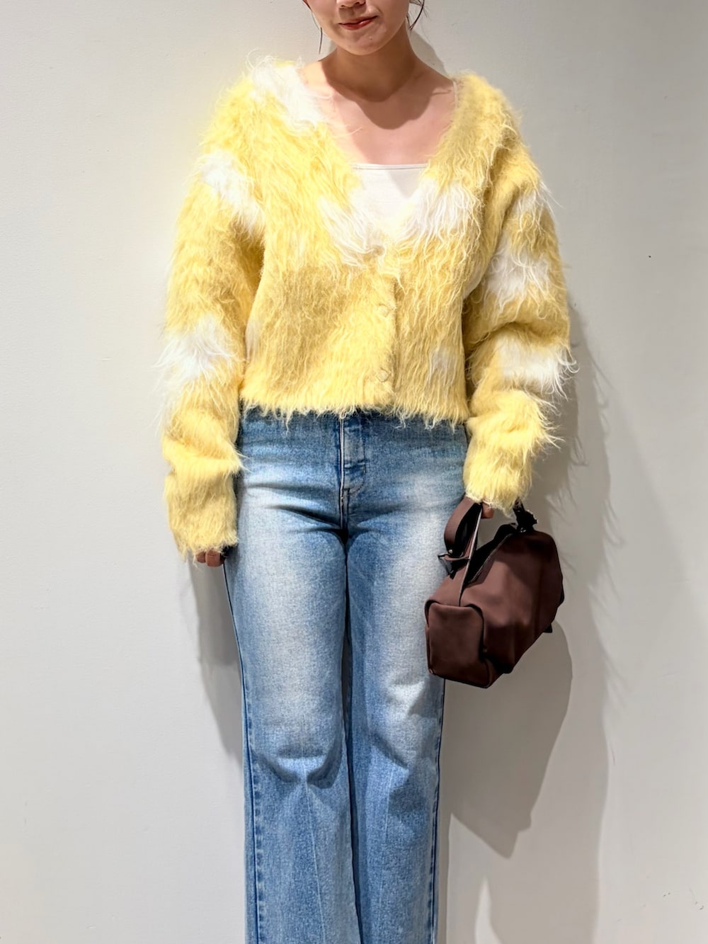 イエロー系のカーディガン/ボレロ、ブルー系のデニムパンツ、ブラック系のブーツを着用したレディースの秋コーディネートの4枚目の写真