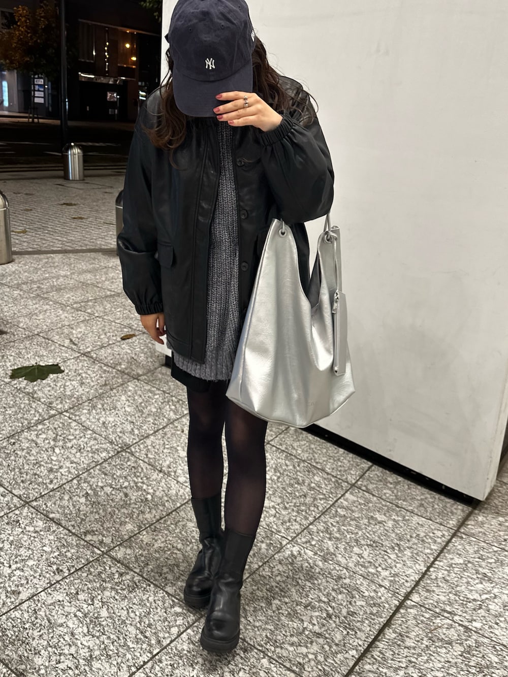 シルバー系のトートバッグ、ブラック系のブーツ、ブルー系のニット/セーターを着用したレディースの秋コーディネートの3枚目の写真