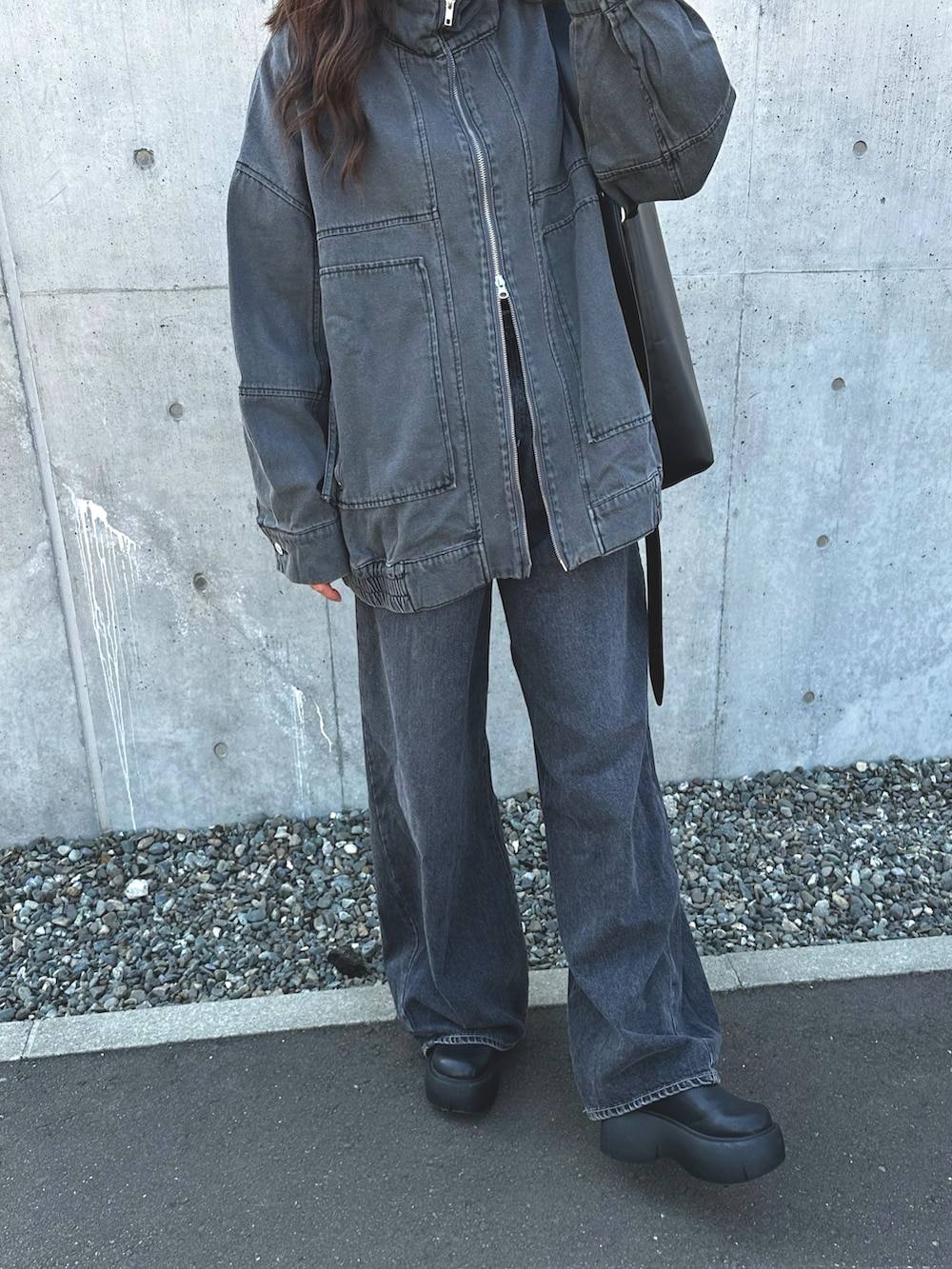 グレー系のブルゾン、ブラック系のデニムパンツ、ブラック系のブーツを着用したレディースの春コーディネートの2枚目の写真