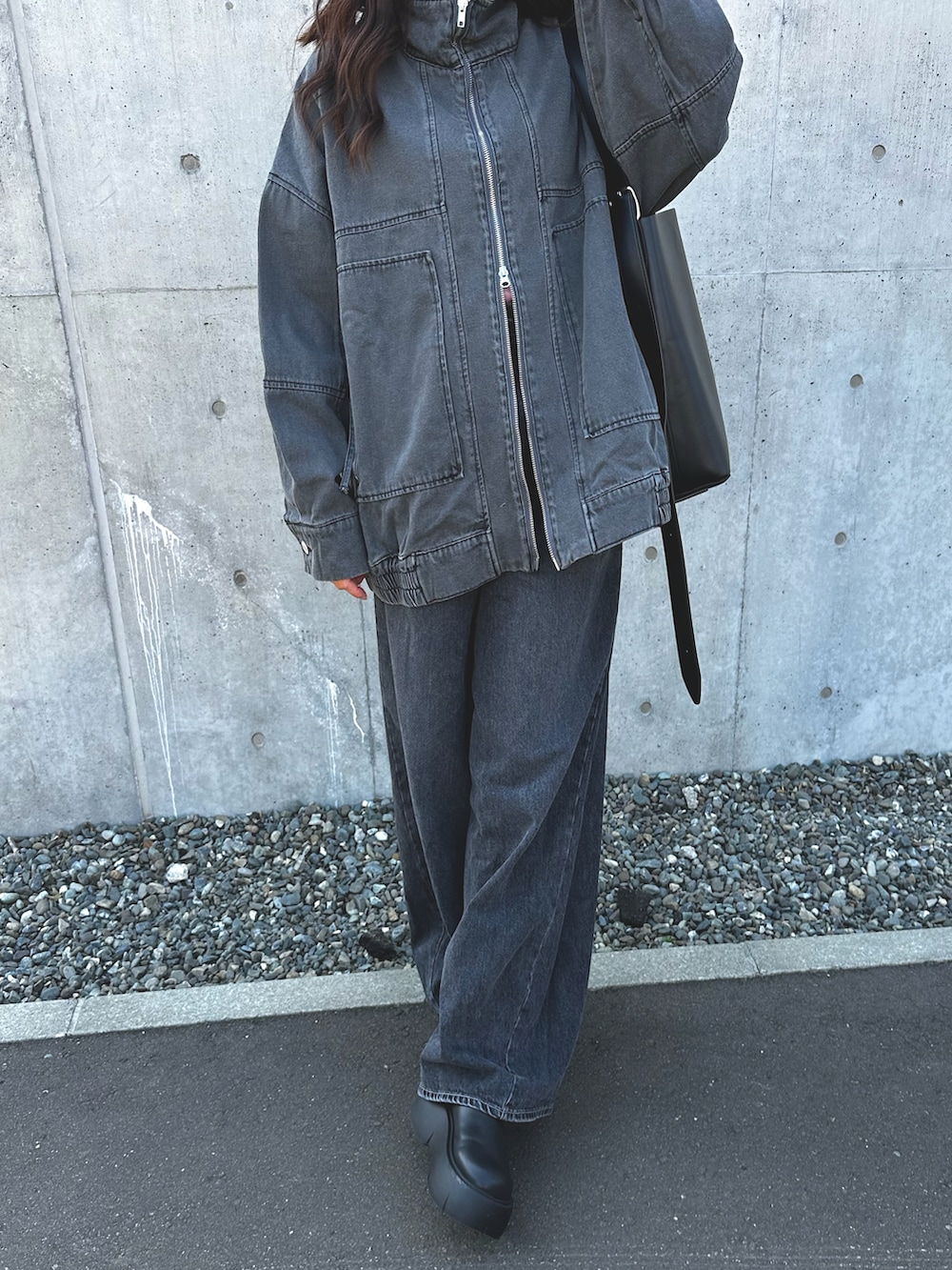 グレー系のブルゾン、ブラック系のデニムパンツ、ブラック系のブーツを着用したレディースの春コーディネートの3枚目の写真