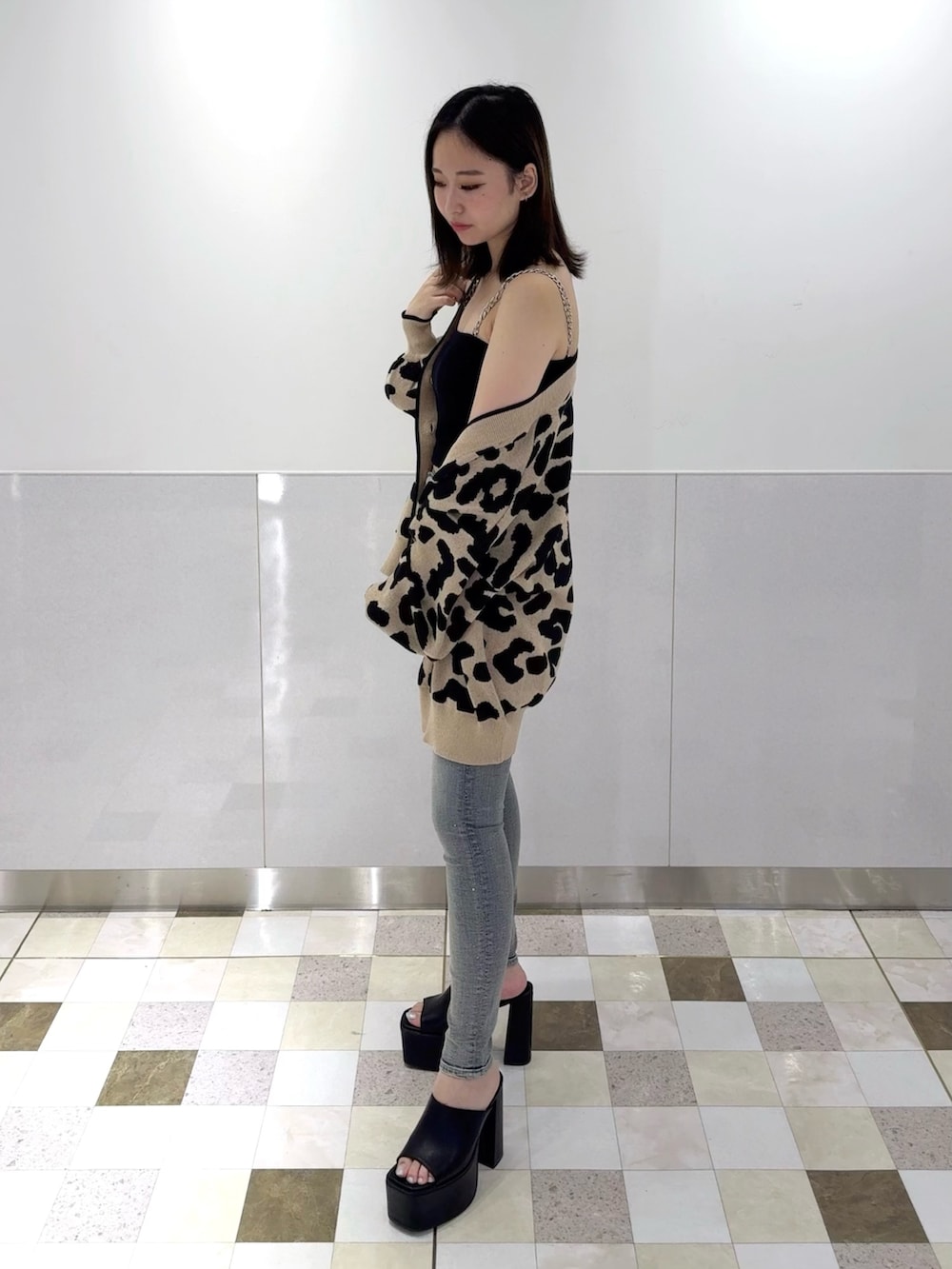 ブラック系のチューブトップ、ベージュ系のカーディガン/ボレロ、ブルー系のデニムパンツを着用したレディースの夏コーディネートの2枚目の写真