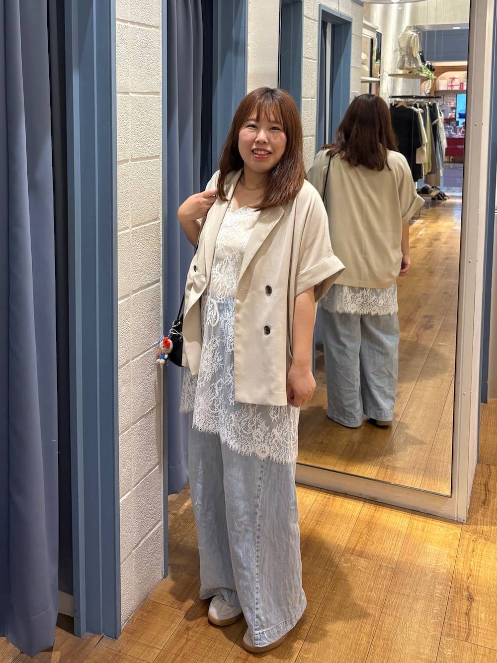 ブルー系のデニムパンツ、ホワイト系のタンクトップ、ホワイト系のテーラードジャケットを着用したレディースの春コーディネートの2枚目の写真