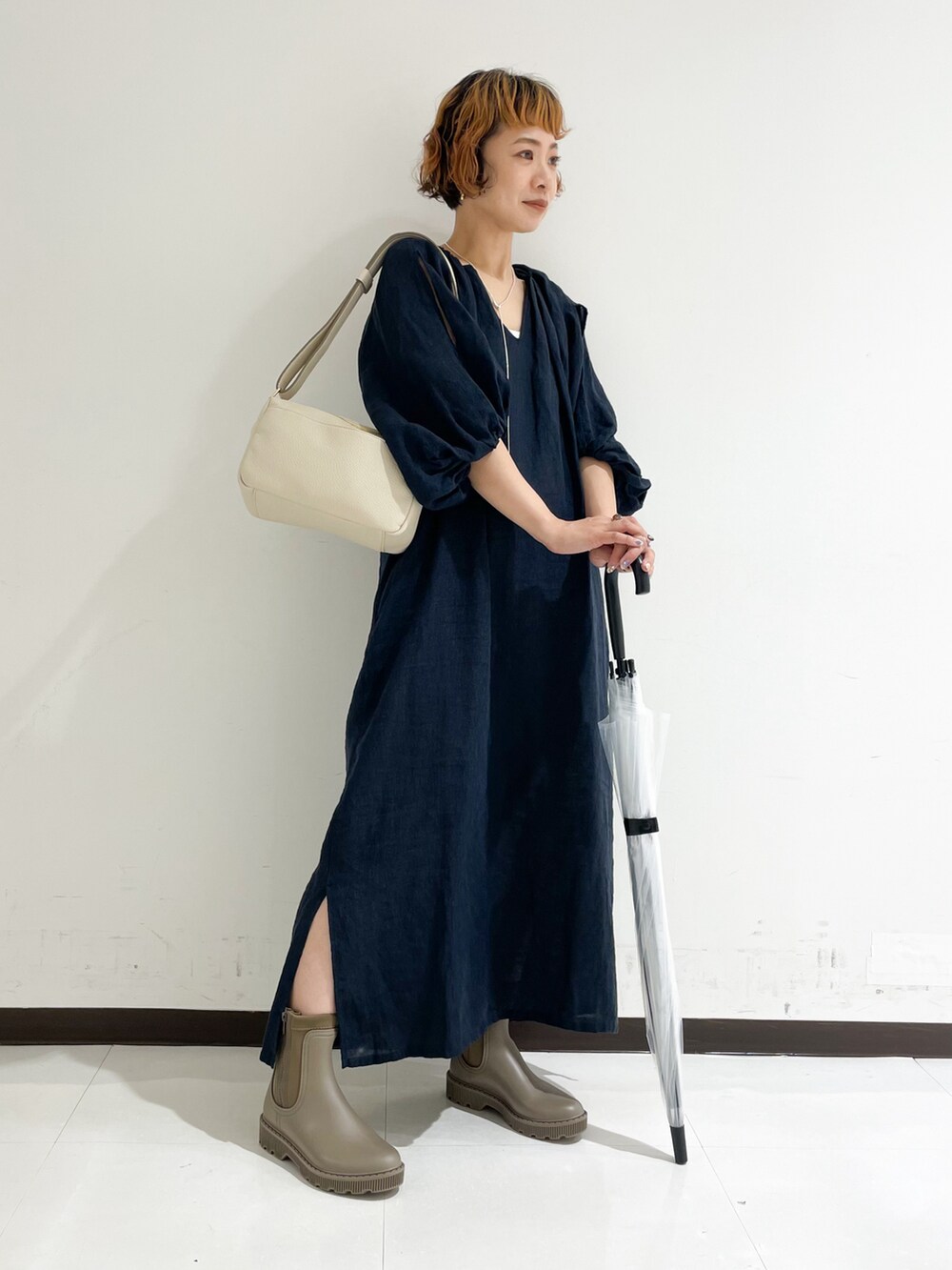 ベージュ系のレインシューズ、ホワイト系のショルダーバッグを着用したレディースの夏コーディネートの2枚目の写真