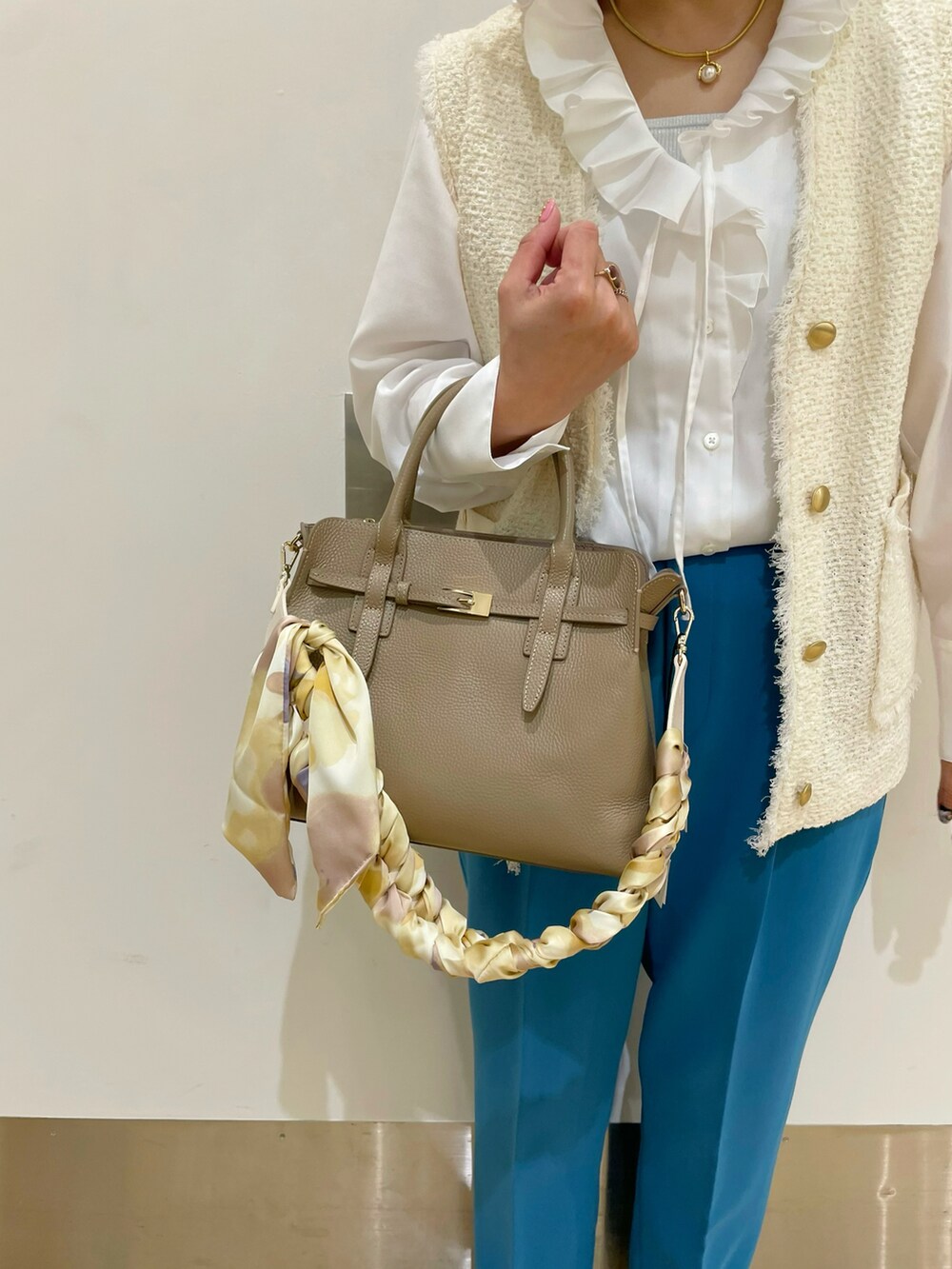 ベージュ系のトートバッグ、ホワイト系のシャツ/ブラウス、ホワイト系のベストを着用したレディースの冬コーディネートの3枚目の写真