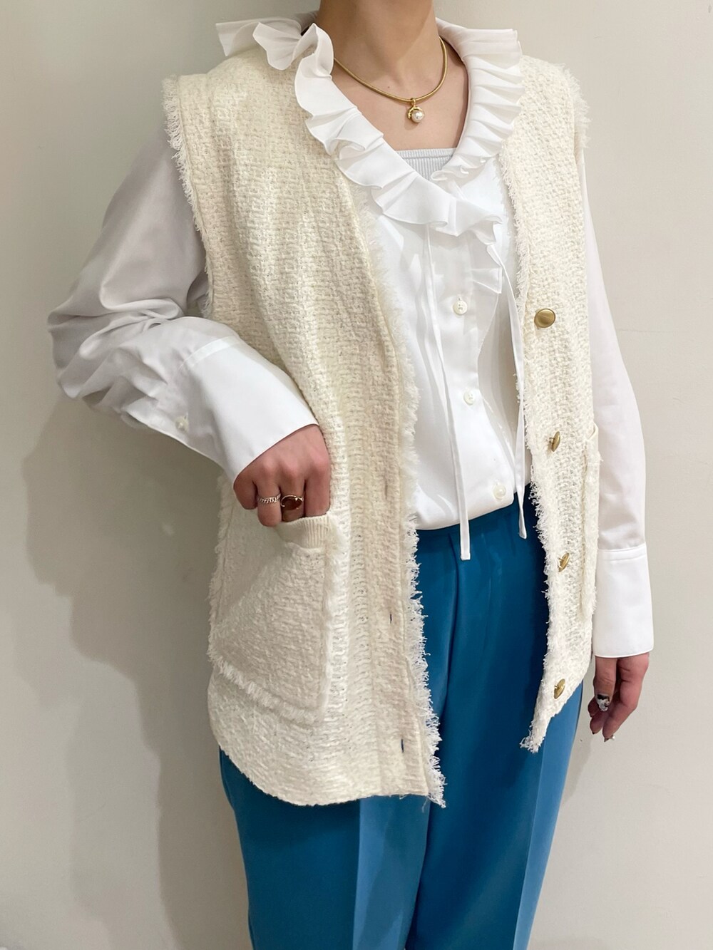 ベージュ系のトートバッグ、ホワイト系のシャツ/ブラウス、ホワイト系のベストを着用したレディースの冬コーディネートの2枚目の写真