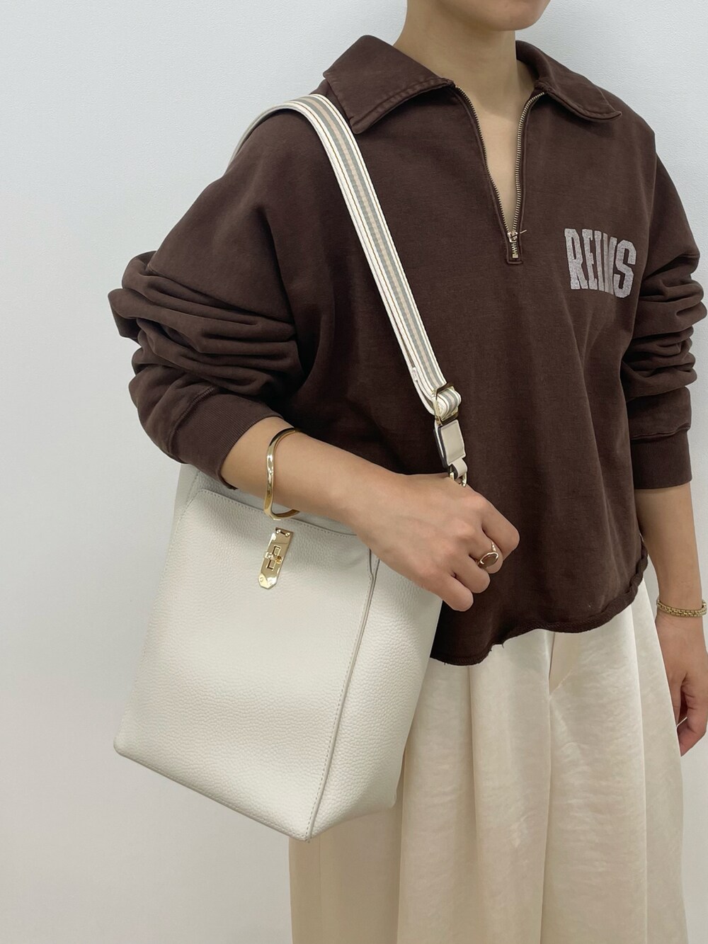ホワイト系のトートバッグ、ホワイト系のショルダーバッグ、ブラウン系のTシャツ/カットソーを着用したレディースの冬コーディネートの5枚目の写真