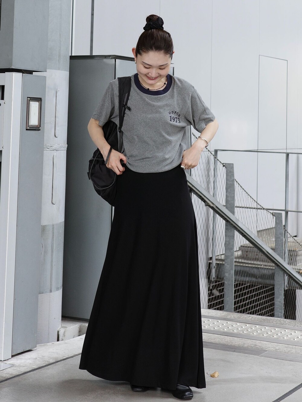 ブラック系のスカート、グレー系のTシャツ/カットソー、ブラック系のバックパック/リュックを着用したレディースの夏コーディネートの2枚目の写真