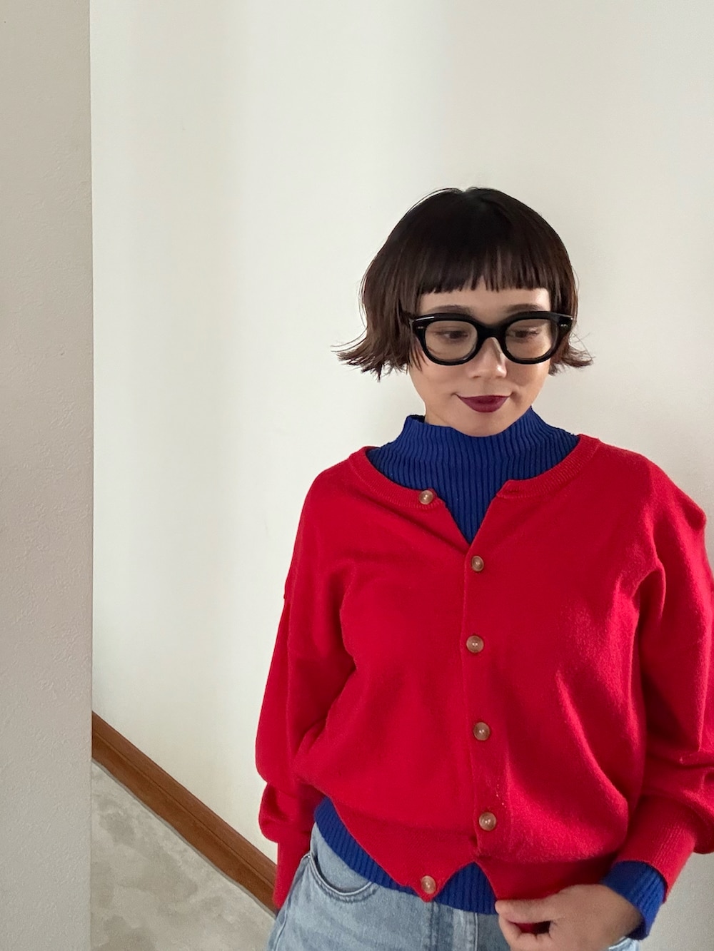 レッド系のカーディガン/ボレロ、ブルー系のデニムパンツ、ブルー系のニット/セーターを着用したレディースの秋コーディネートの3枚目の写真