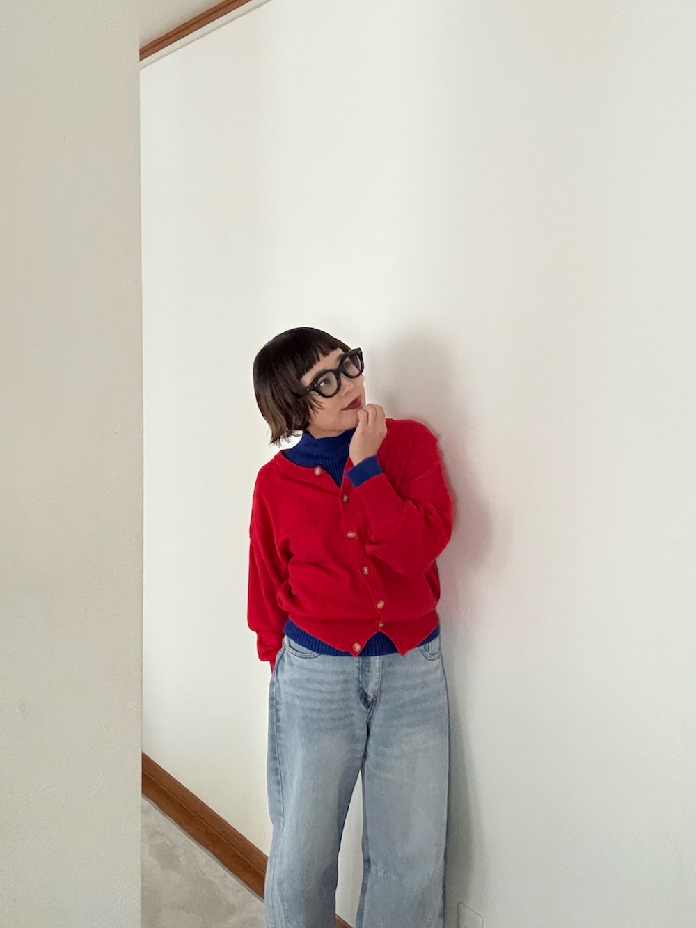 レッド系のカーディガン/ボレロ、ブルー系のデニムパンツ、ブルー系のニット/セーターを着用したレディースの秋コーディネートの2枚目の写真