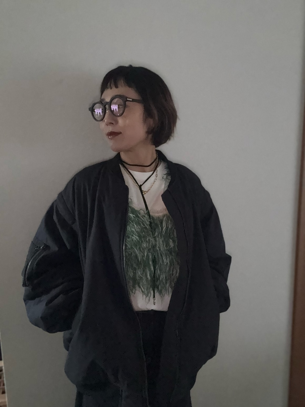 グリーン系のベスト、ブラック系のMA-1、ブラック系のメガネを着用したレディースの冬コーディネートの2枚目の写真