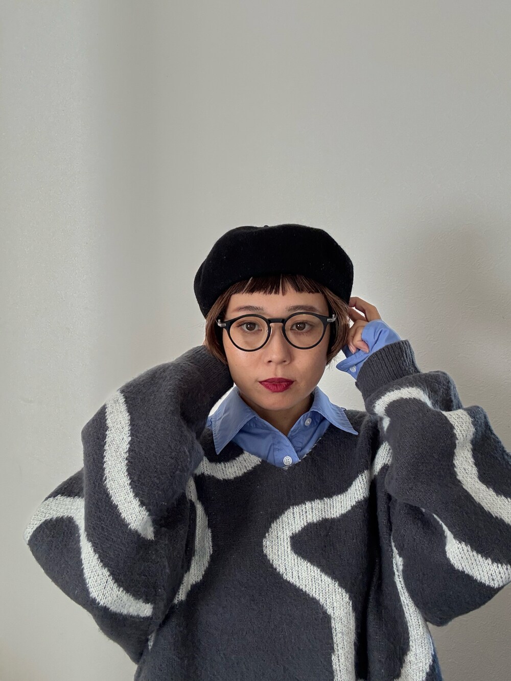 グレー系のニット/セーター、ブルー系のシャツ/ブラウスを着用したレディースの秋コーディネートの2枚目の写真