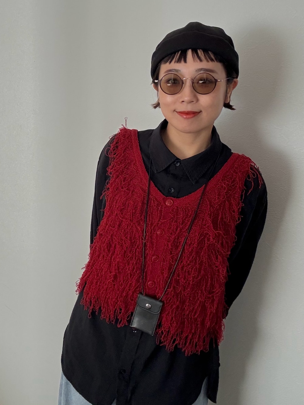 レッド系のベスト、ブルー系のデニムパンツを着用したレディースの秋コーディネートの2枚目の写真