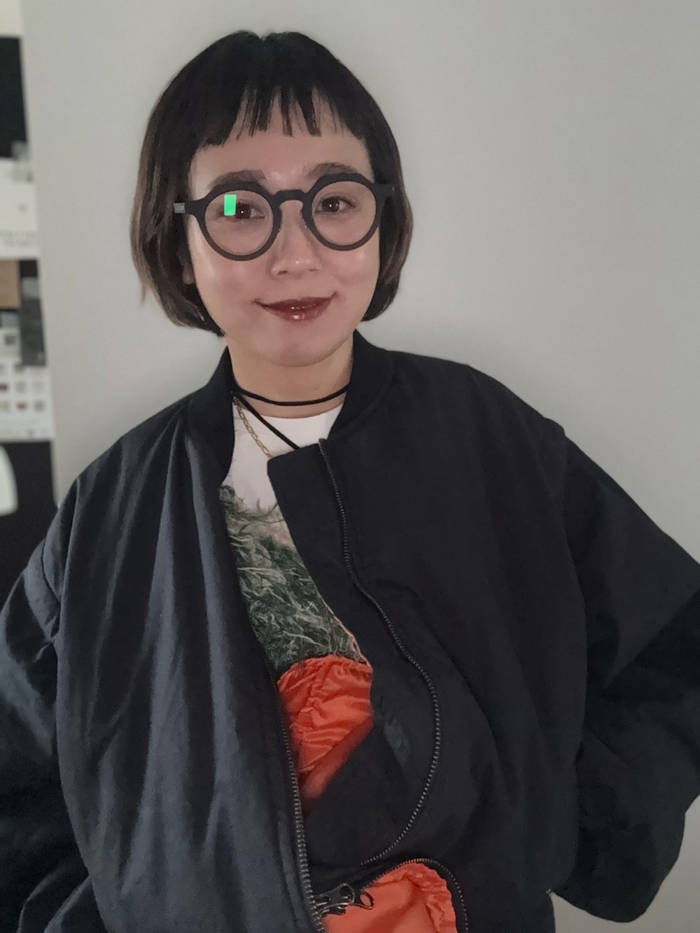 グリーン系のベスト、ブラック系のMA-1、ブラック系のメガネを着用したレディースの冬コーディネートの3枚目の写真