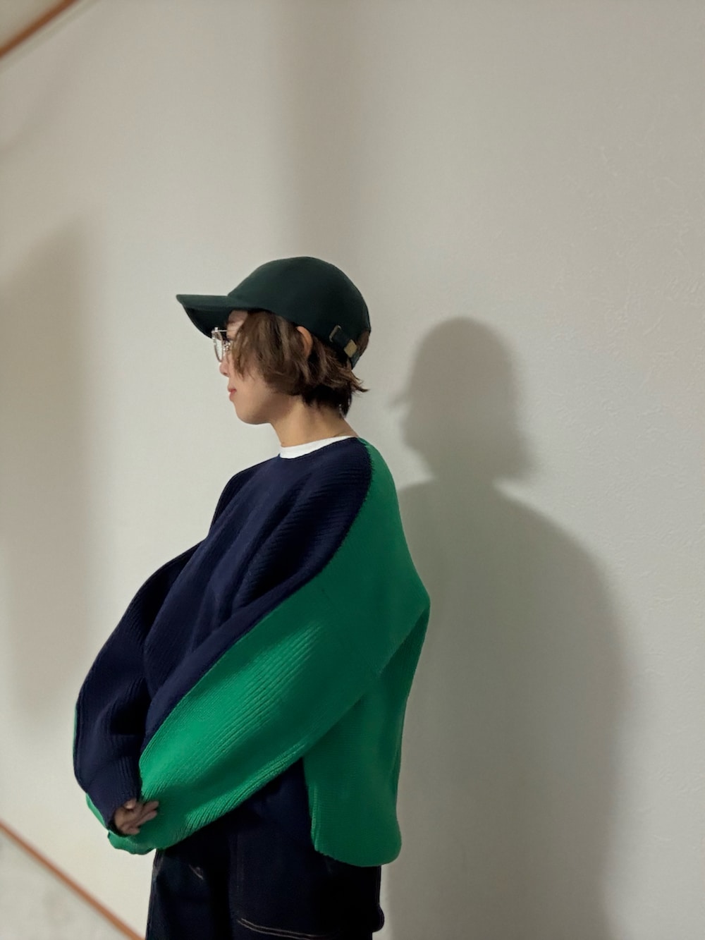 ブルー系のニット/セーター、ブルー系のデニムパンツ、グリーン系のキャップを着用したレディースの秋コーディネートの2枚目の写真