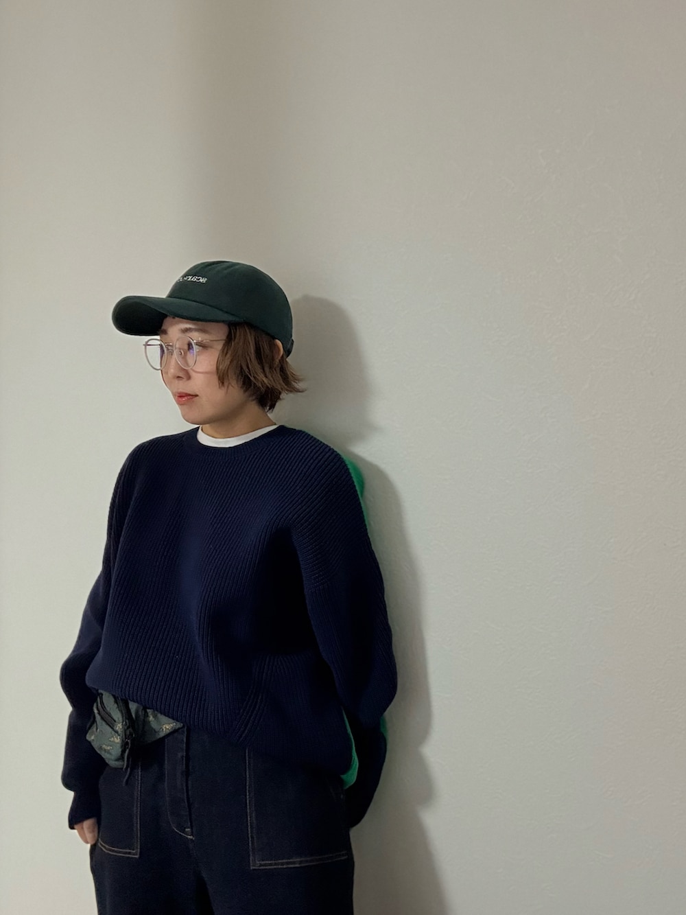 ブルー系のニット/セーター、ブルー系のデニムパンツ、グリーン系のキャップを着用したレディースの秋コーディネートの3枚目の写真