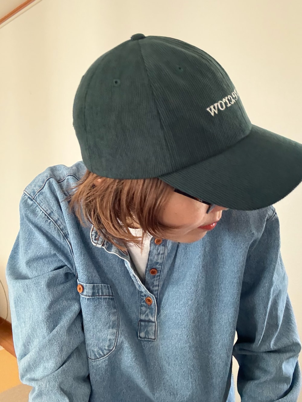 グリーン系のキャップを着用したレディースの秋コーディネートの2枚目の写真