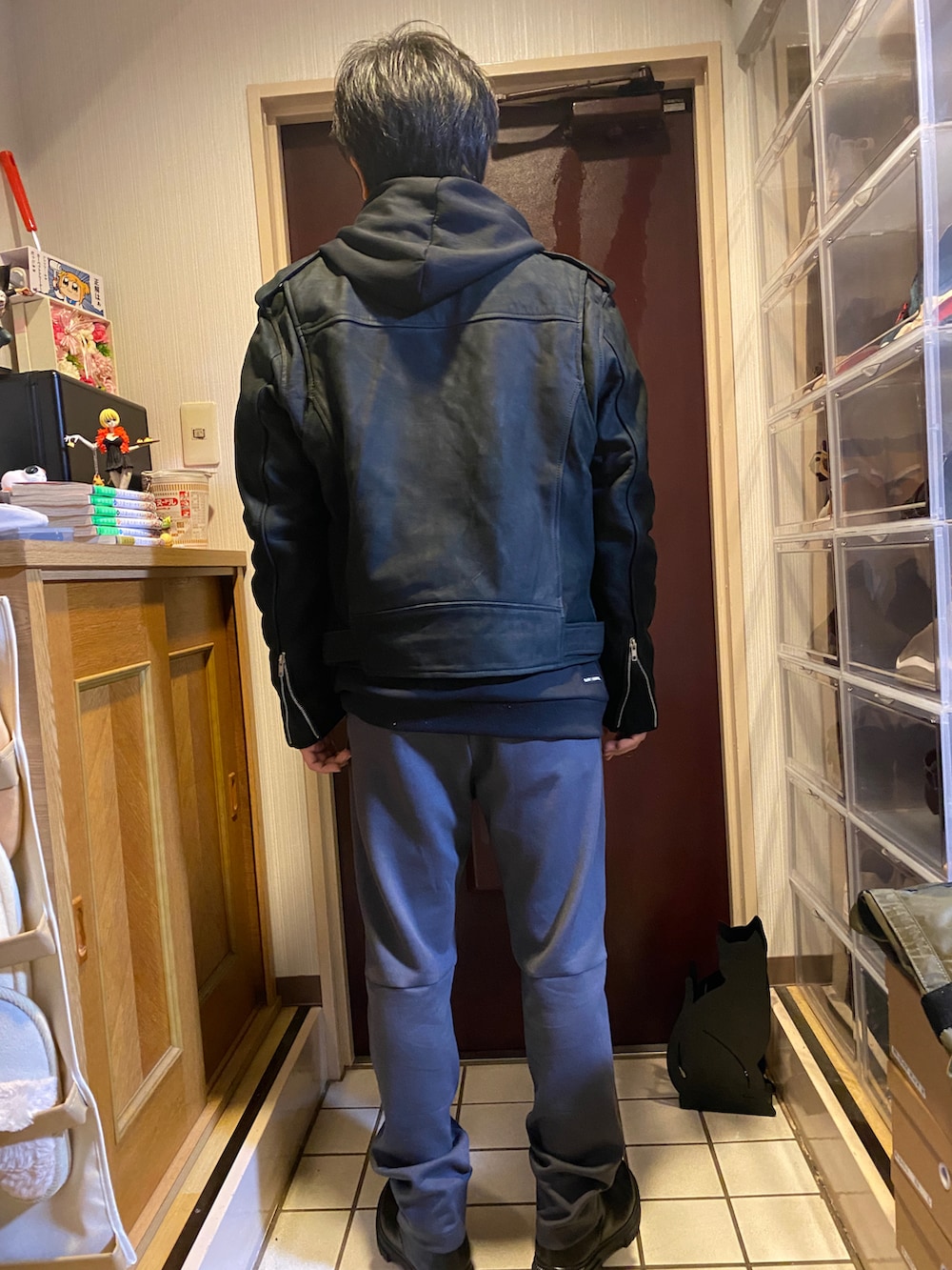 グレー系のスウェットパンツ、ブラック系のパーカー、ブラック系のライダースジャケットを着用したメンズの冬コーディネートの2枚目の写真