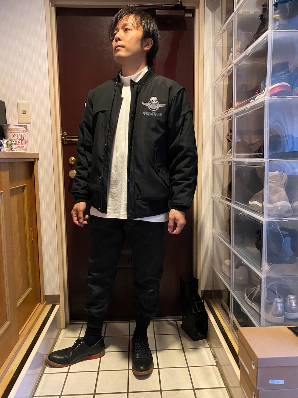 ブラック系のスタジャン、ホワイト系のTシャツ/カットソー、ブラック系のカーゴパンツを着用したメンズの冬コーディネートの3枚目の写真