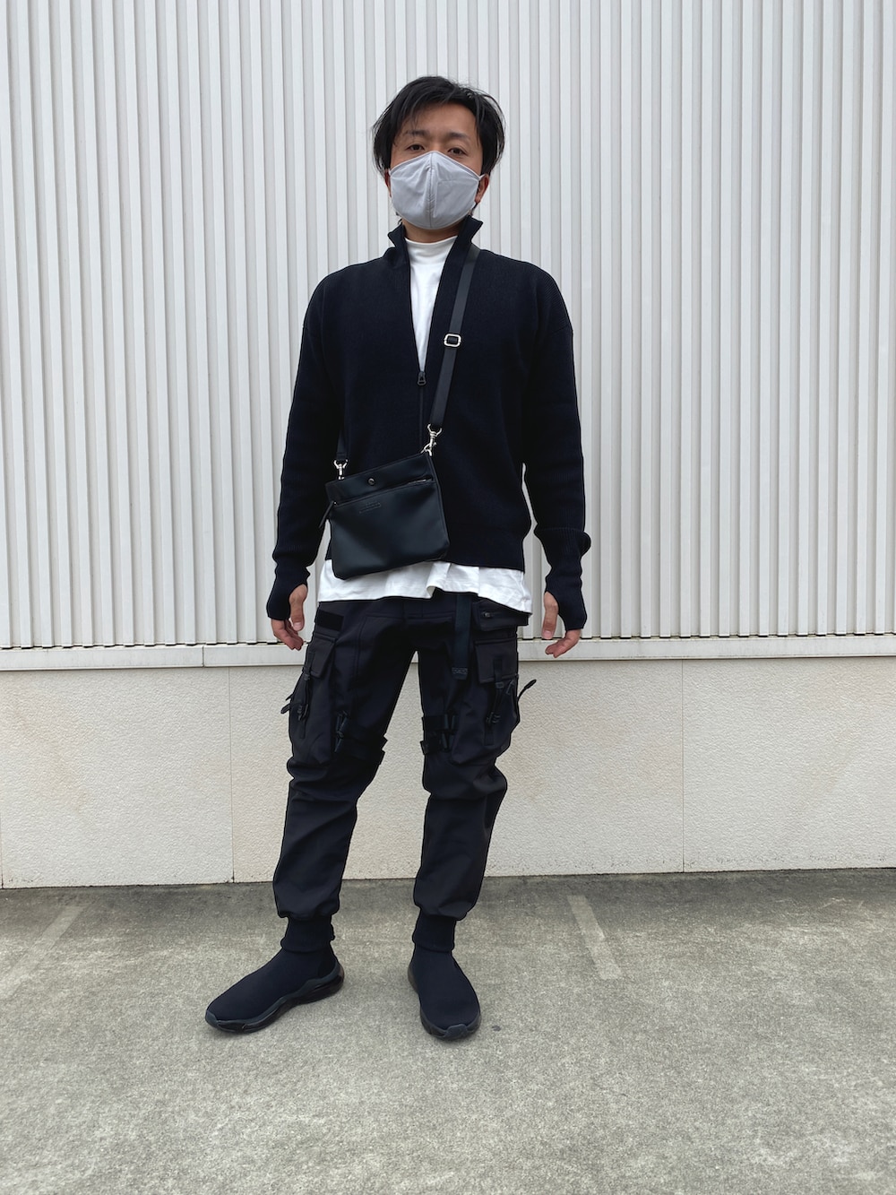 ブラック系のカーゴパンツ、ブラック系のシューズ、ブラック系のショルダーバッグを着用したメンズの秋コーディネートの2枚目の写真