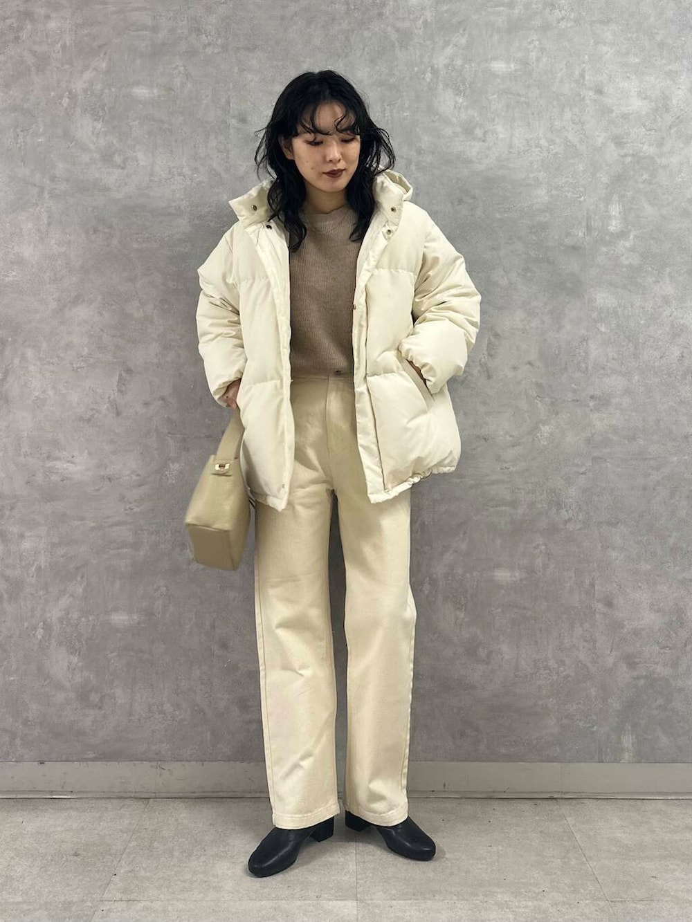 ブラック系のブーツ、ホワイト系のダウンジャケット/コート、ベージュ系のデニムパンツを着用したレディースの冬コーディネートの5枚目の写真