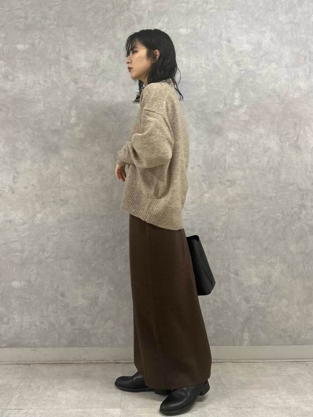 ブラウン系のスカート、ベージュ系のニット/セーター、ブラック系のトートバッグを着用したレディースの冬コーディネートの6枚目の写真