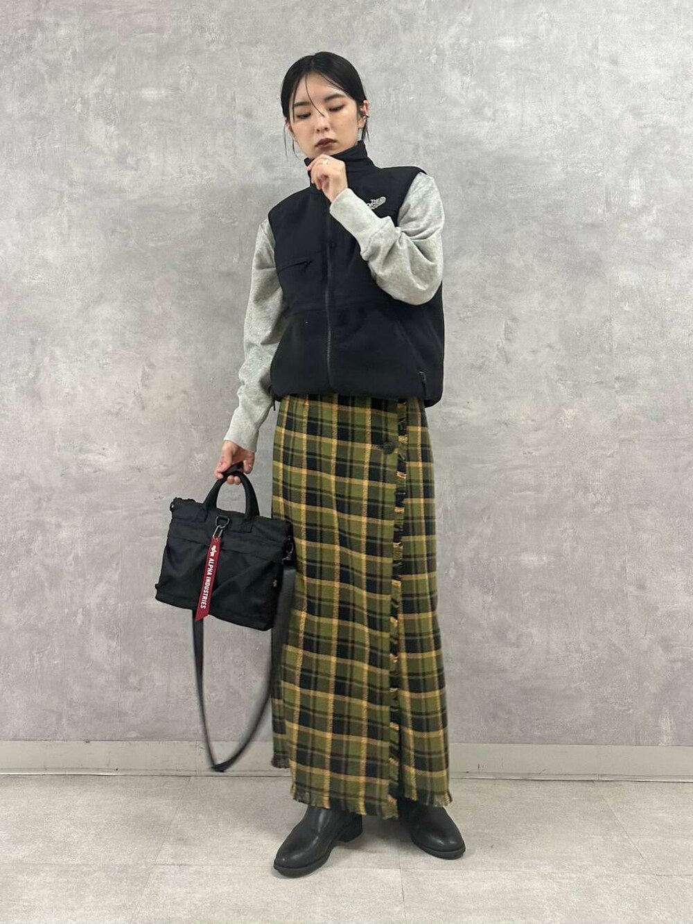 ブラック系のショルダーバッグ、グリーン系のスカート、グレー系のTシャツ/カットソーを着用したレディースの秋コーディネートの2枚目の写真