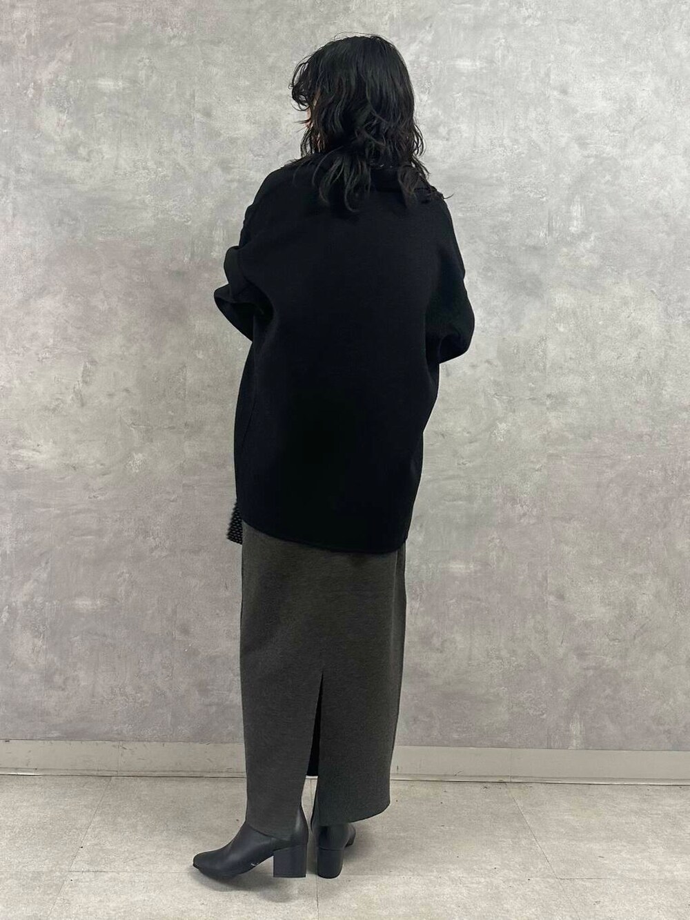 ブラック系のその他アウター、グレー系のスカート、グリーン系のニット/セーターを着用したレディースの冬コーディネートの3枚目の写真