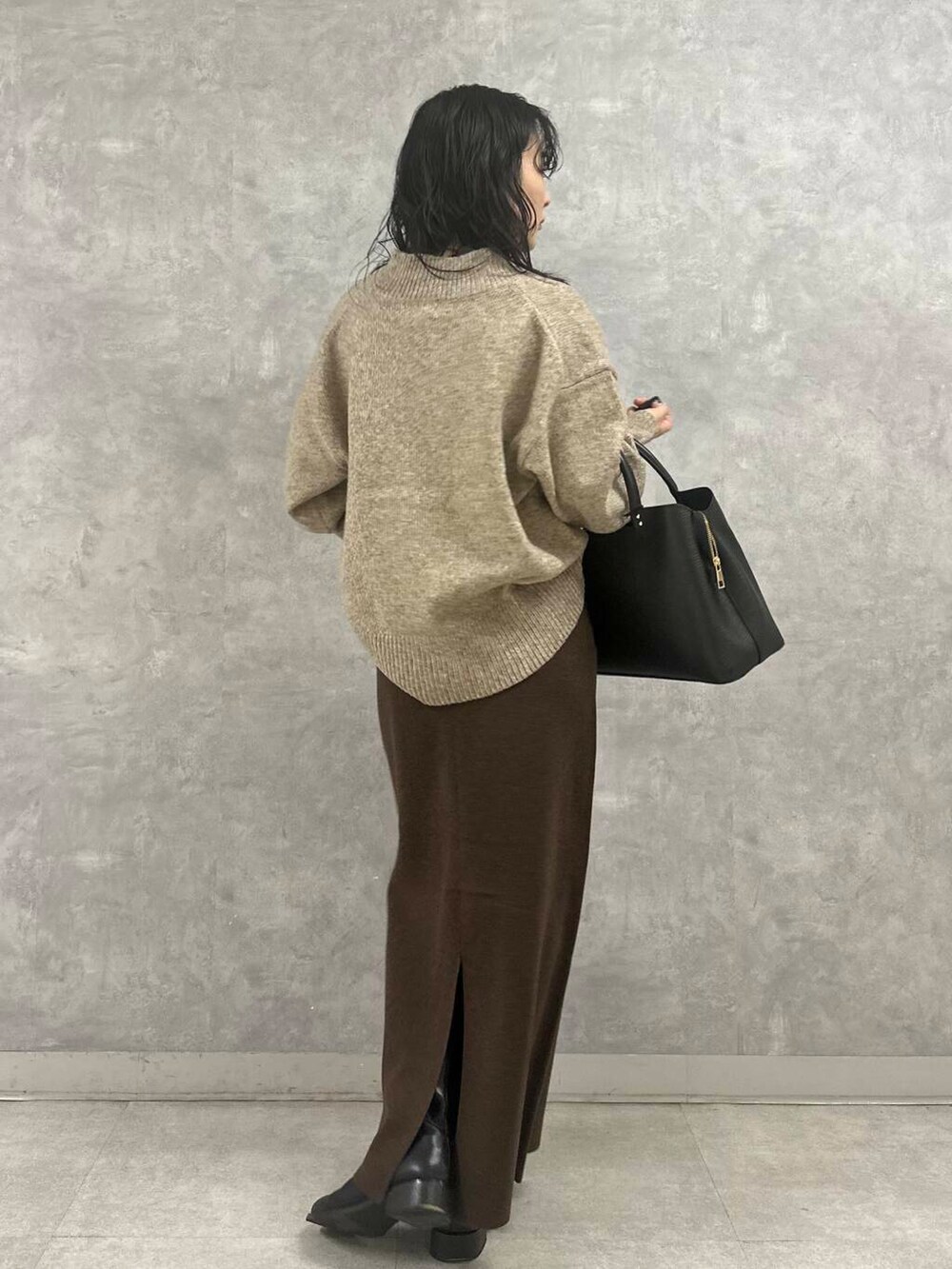 ブラウン系のスカート、ベージュ系のニット/セーター、ブラック系のトートバッグを着用したレディースの冬コーディネートの3枚目の写真