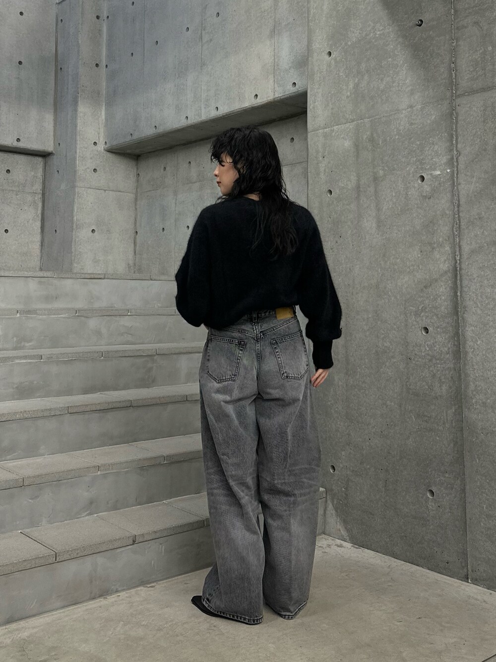 ブラック系のニット/セーター、グレー系のデニムパンツ、ブラック系のブーツを着用したレディースの秋コーディネートの2枚目の写真