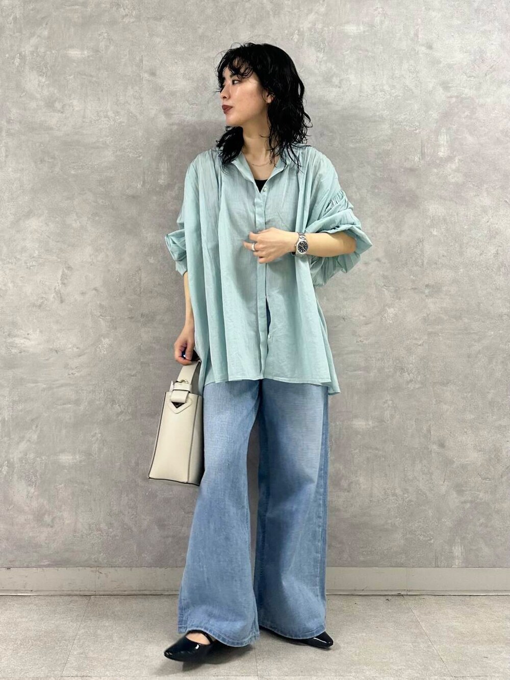 ブルー系のデニムパンツ、ホワイト系のトートバッグ、グリーン系のシャツ/ブラウスを着用したレディースの春コーディネートの2枚目の写真