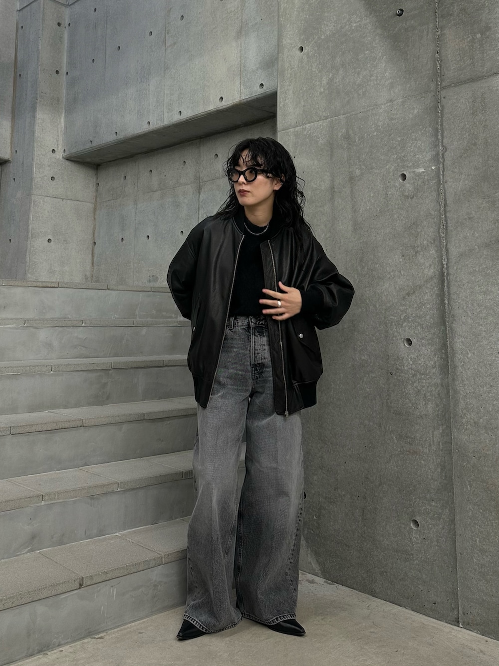 ブラック系のニット/セーター、グレー系のデニムパンツ、ブラック系のブーツを着用したレディースの秋コーディネートの3枚目の写真