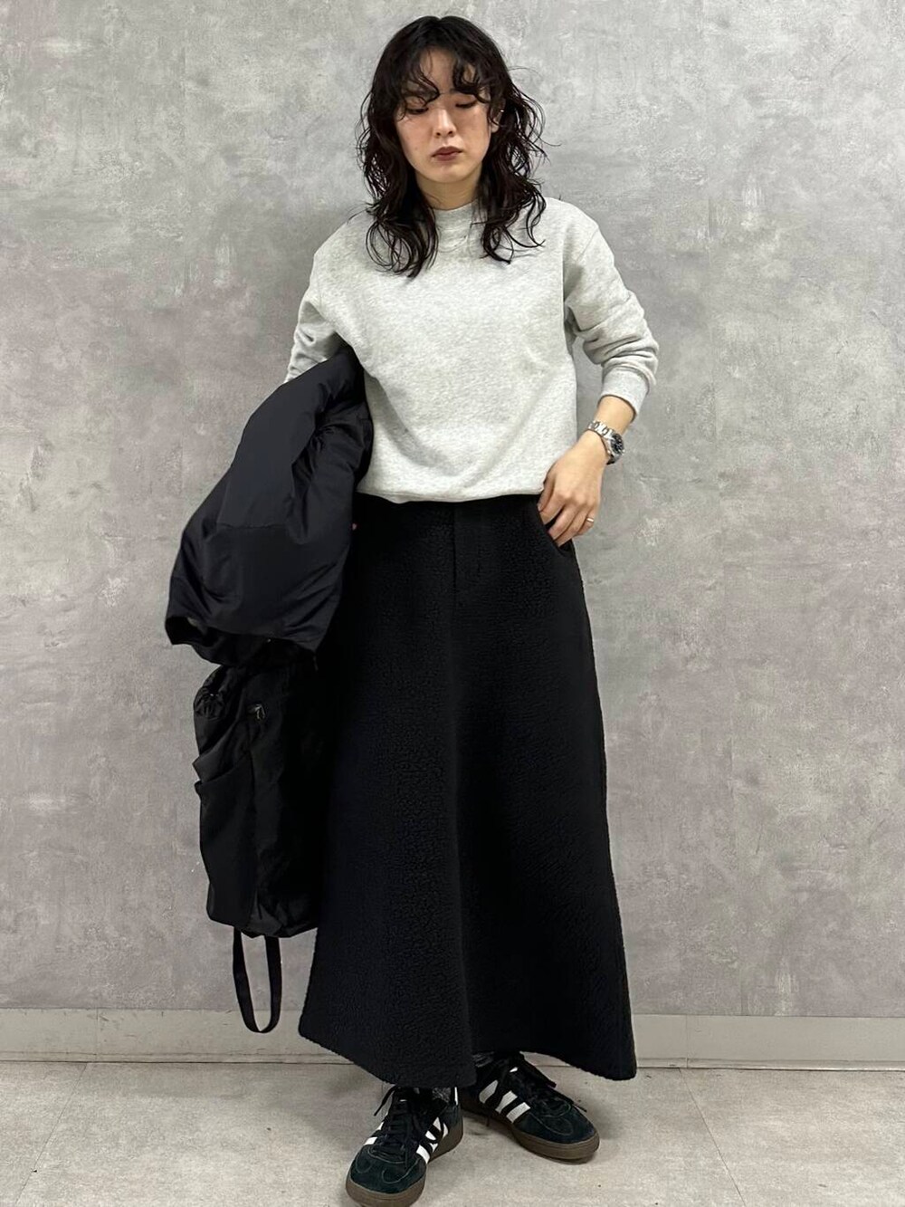 ブラック系のダウンジャケット/コート、グレー系のTシャツ/カットソー、ブラック系のスカートを着用したレディースの冬コーディネートの3枚目の写真