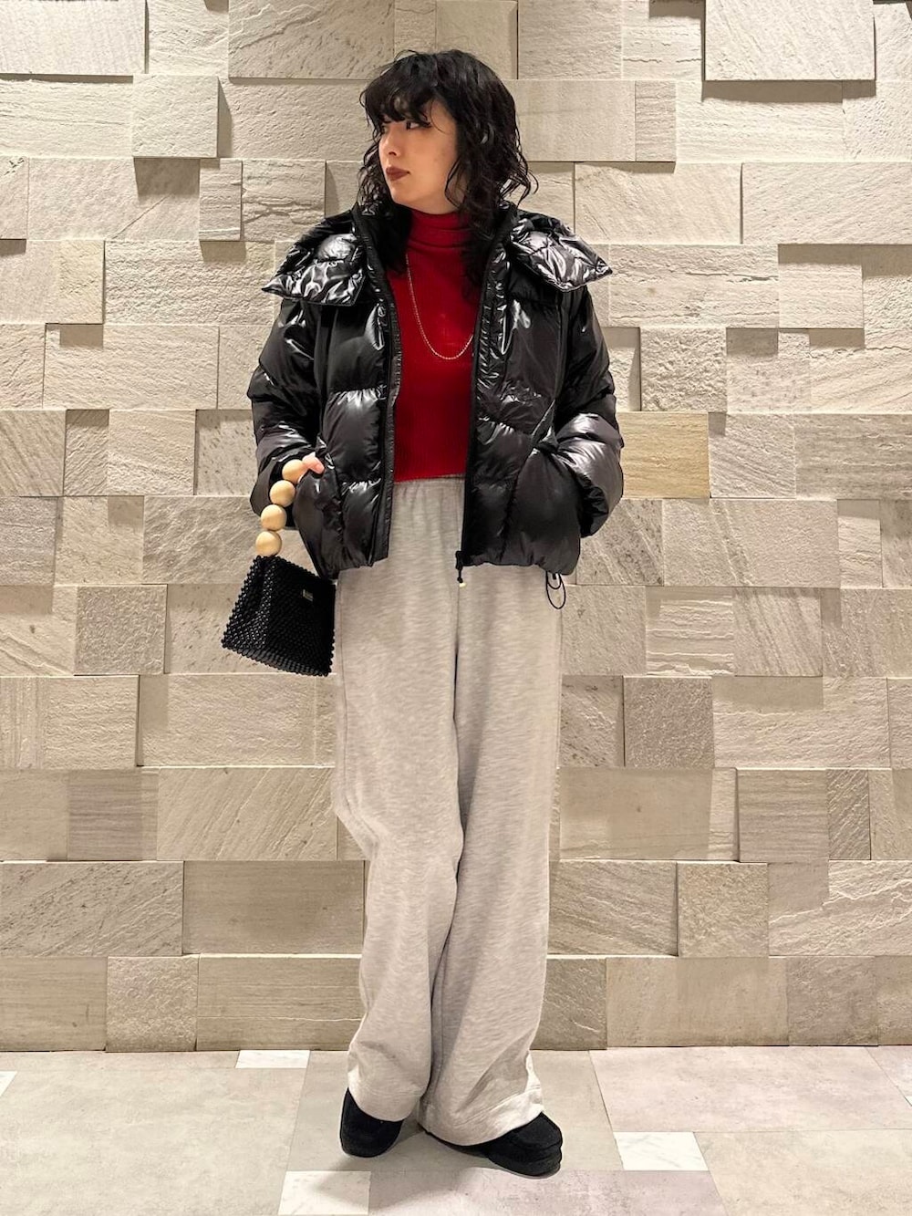 レッド系のニット/セーター、グレー系のその他パンツ、ブラック系のダウンジャケット/コートを着用したレディースの冬コーディネートの3枚目の写真