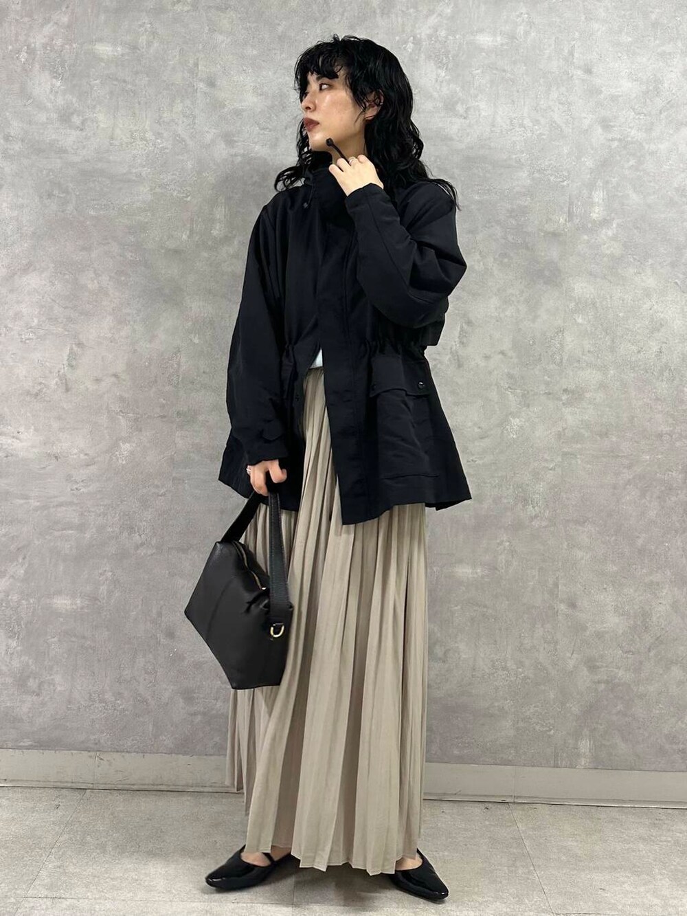 ブラック系のマウンテンパーカー、ブルー系のニット/セーター、ブラック系のショルダーバッグを着用したレディースの春コーディネートの2枚目の写真