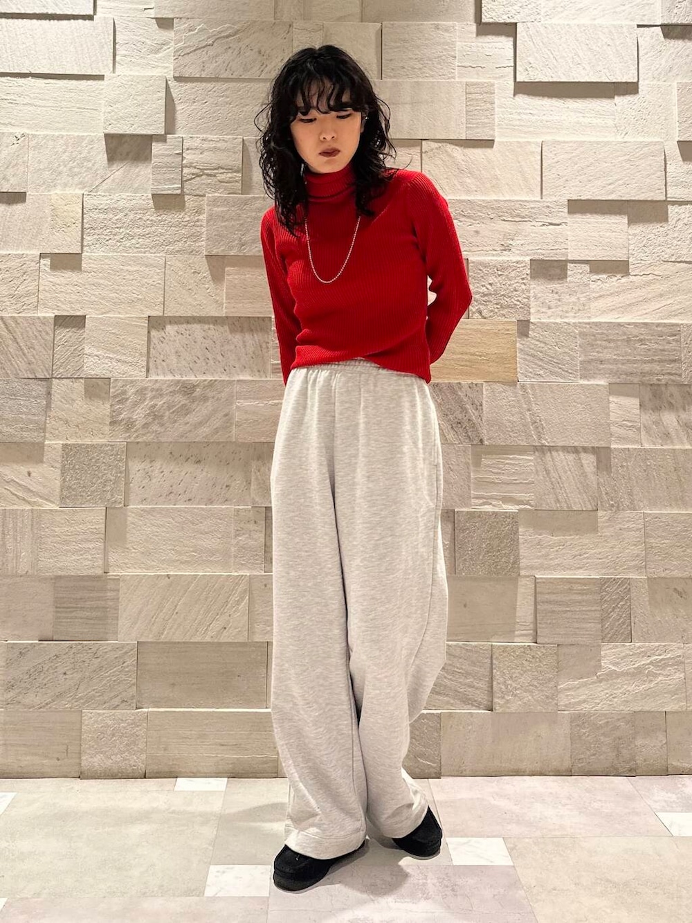 レッド系のニット/セーター、グレー系のその他パンツ、ブラック系のダウンジャケット/コートを着用したレディースの冬コーディネートの4枚目の写真