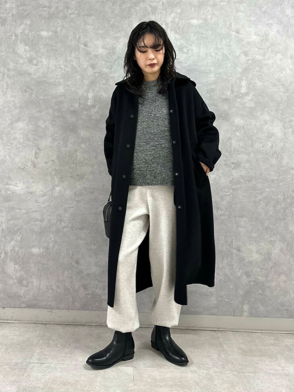 ブラック系のショルダーバッグ、ブラック系のブーツ、ホワイト系のTシャツ/カットソーを着用したレディースの冬コーディネートの2枚目の写真