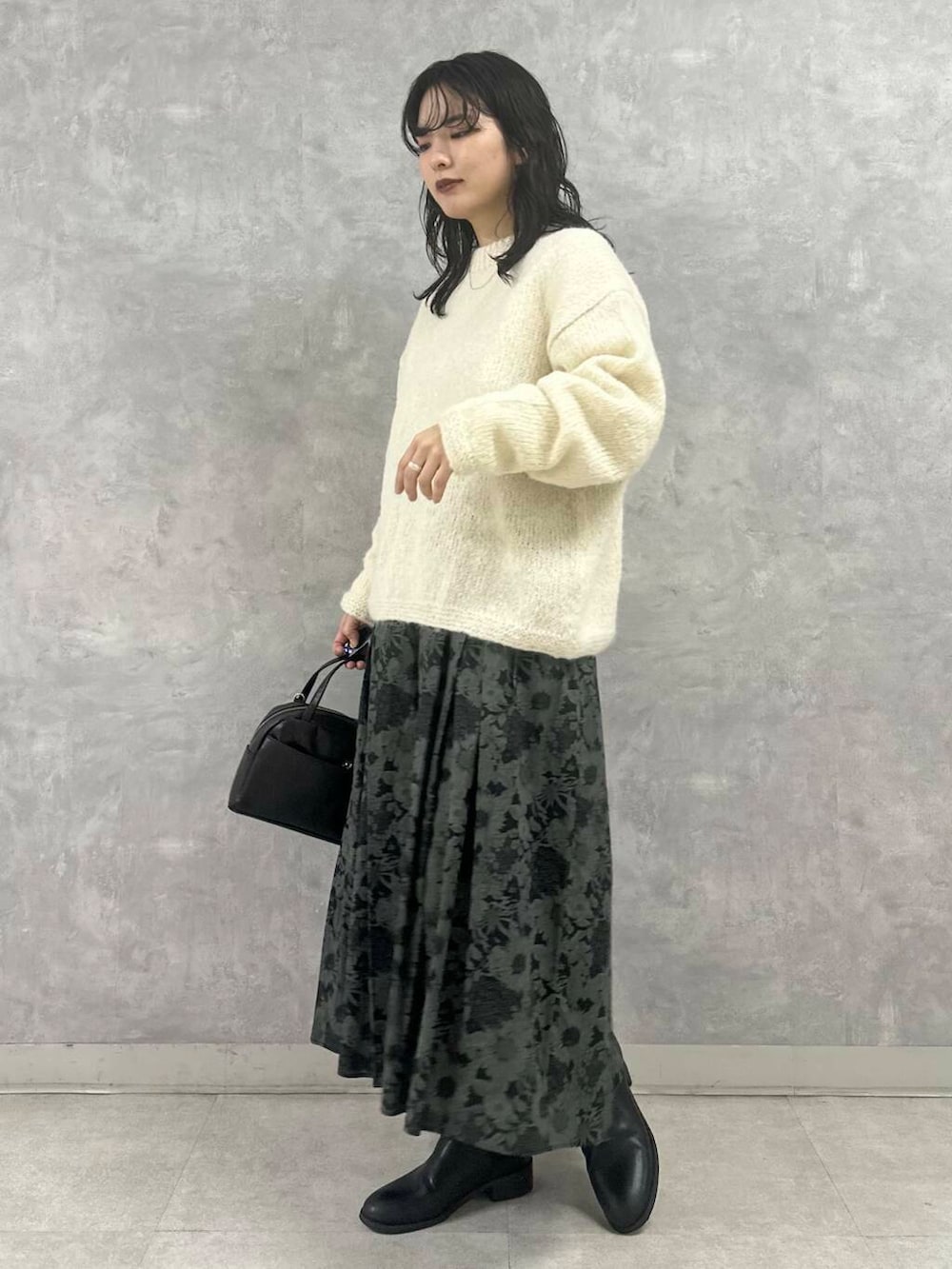 ホワイト系のニット/セーター、ブラック系のスカート、ブラック系のショルダーバッグを着用したレディースの冬コーディネートの2枚目の写真