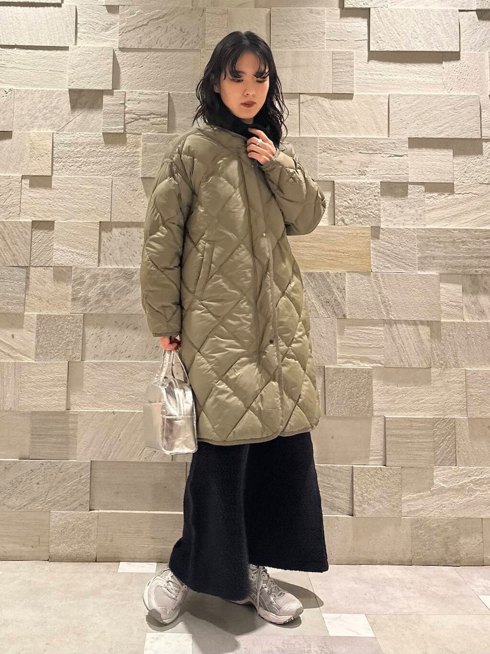 グリーン系のダウンジャケット/コート、ブラック系のスウェット、シルバー系のショルダーバッグを着用したレディースの秋コーディネートの2枚目の写真