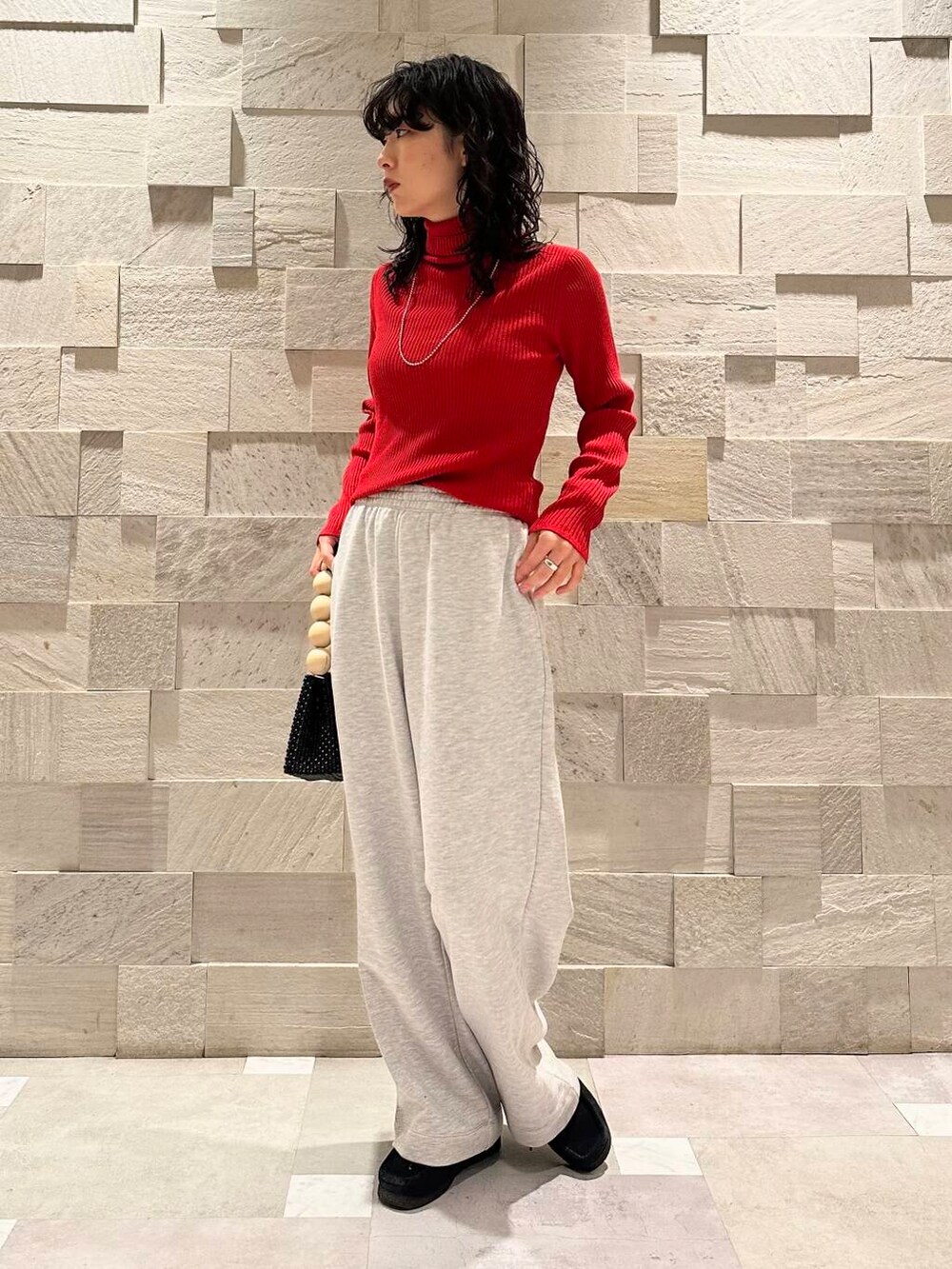 レッド系のニット/セーター、グレー系のその他パンツ、ブラック系のダウンジャケット/コートを着用したレディースの冬コーディネートの5枚目の写真