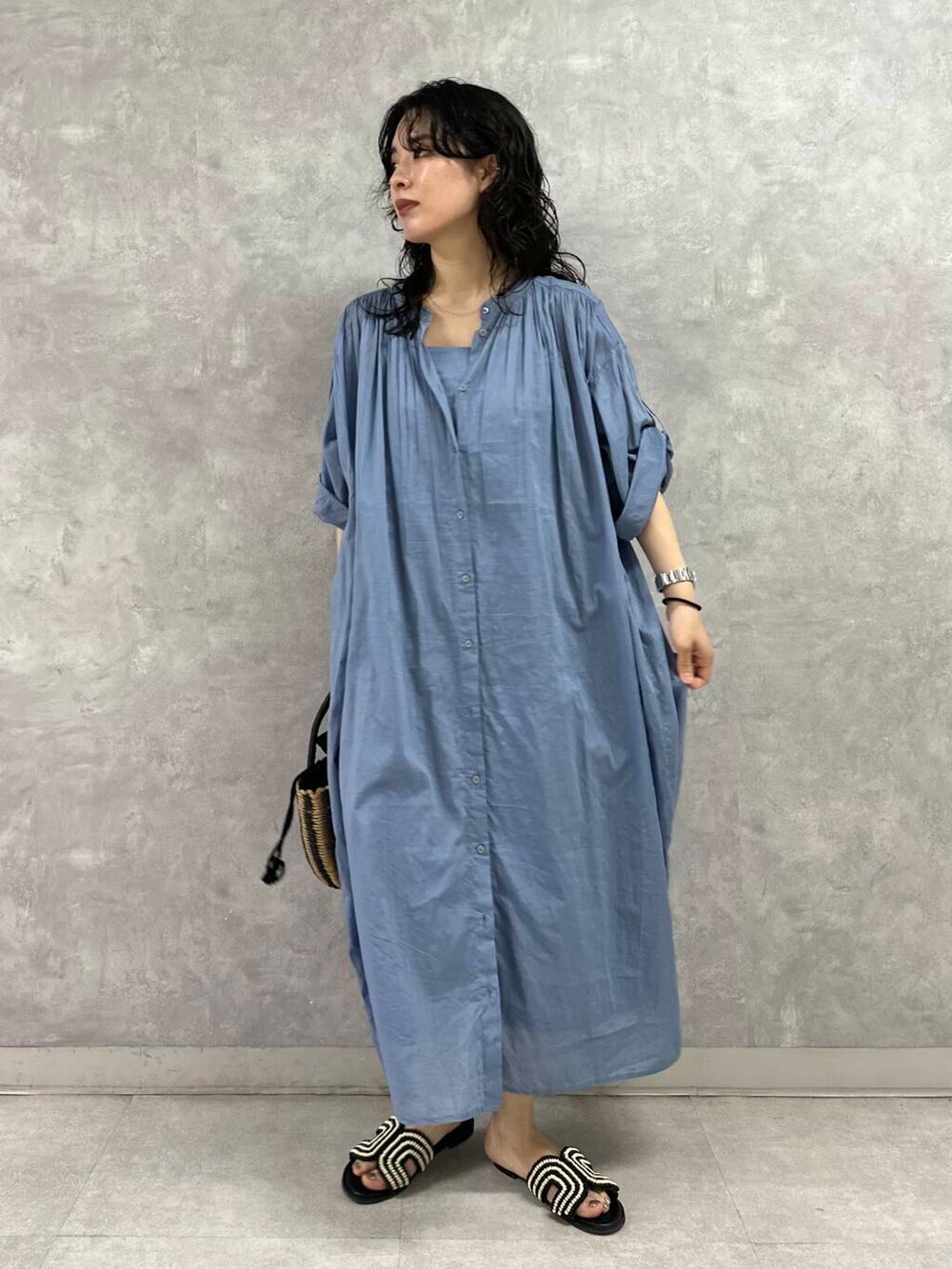 ブラック系のハンドバッグ、ブルー系のワンピース、ブラック系のサンダルを着用したレディースの夏コーディネートの2枚目の写真