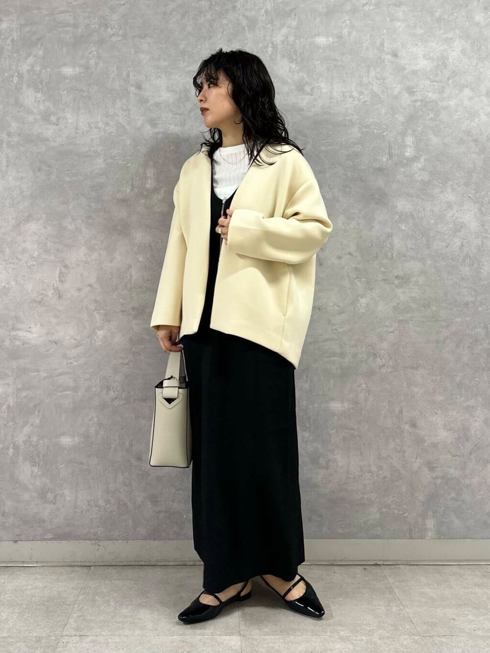 ブラック系のワンピース、ホワイト系のノーカラージャケット、ホワイト系のTシャツ/カットソーを着用したレディースの春コーディネートの2枚目の写真