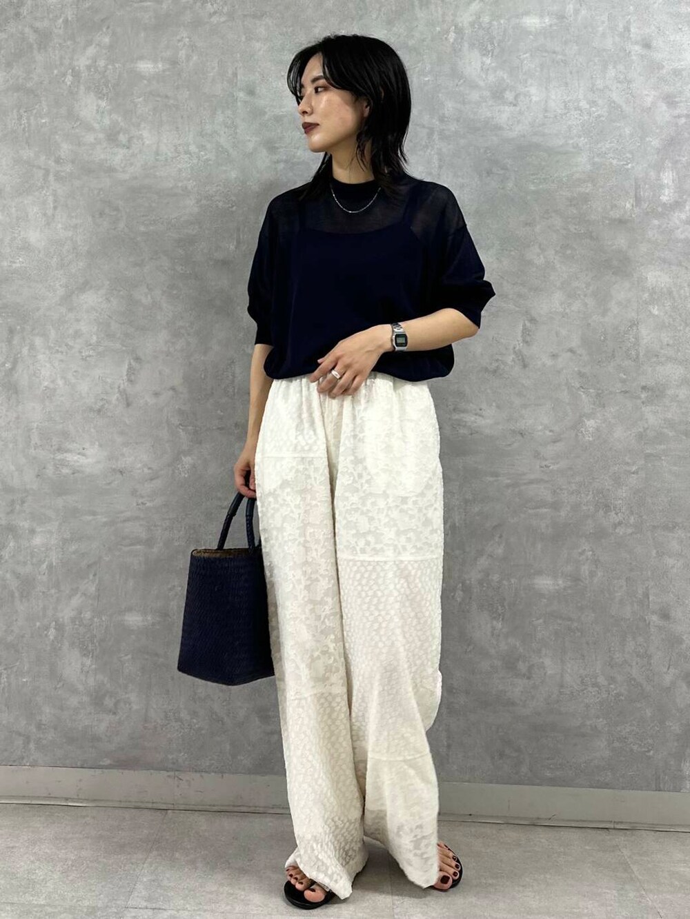 ブルー系のトートバッグ、ブラック系のサンダル、ブラック系のニット/セーターを着用したレディースの夏コーディネートの2枚目の写真