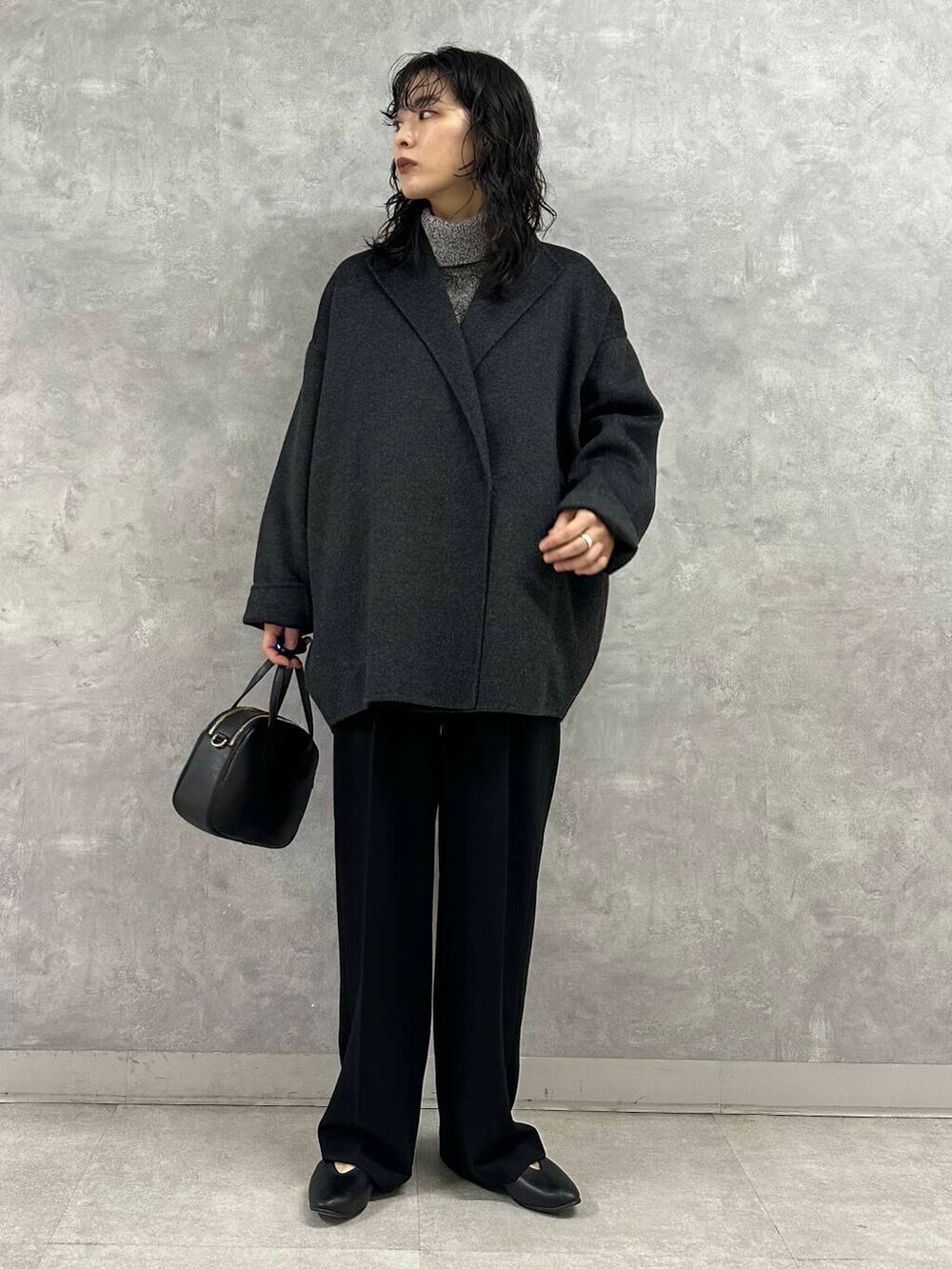 グレー系のその他アウター、ブラック系のニット/セーター、ブラック系のショルダーバッグを着用したレディースの冬コーディネートの2枚目の写真