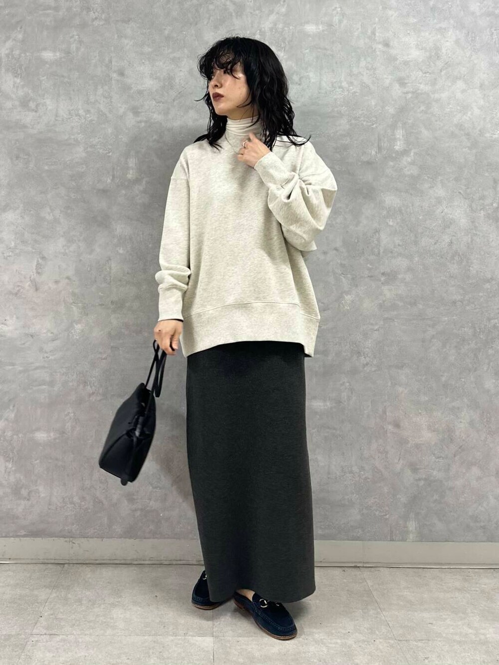 グレー系のスカート、ブラック系のショルダーバッグ、ホワイト系のTシャツ/カットソーを着用したレディースの冬コーディネートの2枚目の写真